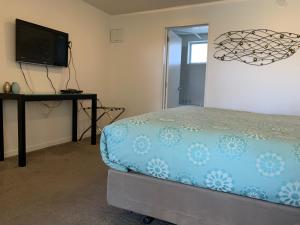 a bedroom with a bed and a desk and a television at Salerno Motel Apartments in Christchurch