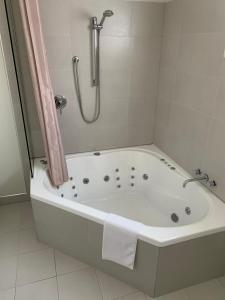 a bathroom with a bath tub with a shower at Salerno Motel Apartments in Christchurch