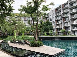 una piscina frente a un edificio con sillas y un árbol en 23 Estate Khaoyai Tropical Style, en Ban Huai Sok Noi