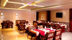 a restaurant with tables and chairs and a flat screen tv at Hotel Emerald Regency in Putuppalli