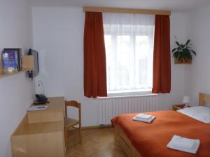 a bedroom with a bed and a desk and a window at Hotel Garni Rambousek in Prague