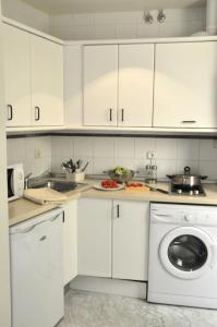 a kitchen with white cabinets and a dishwasher at Apartamentos Turísticos Los Girasoles II in Granada