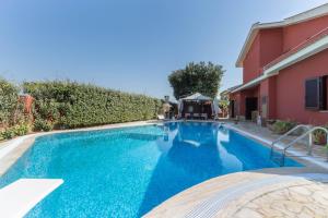 a swimming pool next to a house with blue water at Stella in Quartu SantʼElena