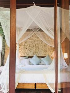 een slaapkamer met een hemelbed met witte lakens en kussens bij Dragon House - Your Dream House in Bali! in Ubud
