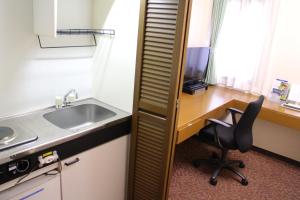 a kitchen with a desk and a sink and a chair at Business Hotel Raicho in Koshigaya