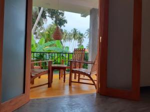 an open door to a balcony with chairs and a table at Om Villa in Hikkaduwa