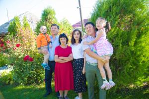 a family posing for a picture in a garden at Happy Nomads Yurt Camp & Hostel in Karakol