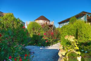 a garden with flowers and a house in the background at Happy Nomads Yurt Camp & Hostel in Karakol