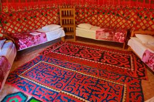 Habitación con 2 camas y alfombra. en Happy Nomads Yurt Camp & Hostel en Karakol