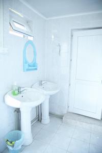 a white bathroom with two sinks and a mirror at Happy Nomads Yurt Camp & Hostel in Karakol