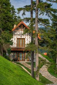 una casa su una collina con alberi in primo piano di Foleya Mountain Resort Hotel & Villas a Trabzon