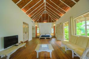 a living room with a couch and a tv at Trikora Beach Club and Resort in Telukbakau