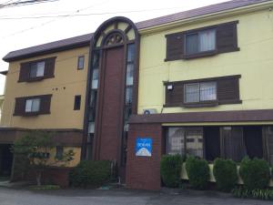 a yellow and brown building with a blue sign on it at Resort Inn Seikan in Hakuba