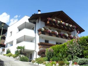 a white building with flowers on a balcony at Appartements Pixner in Saltusio