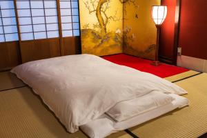 a white bed in a room with a lamp at Machiya Kanazawa Kikunoya in Kanazawa