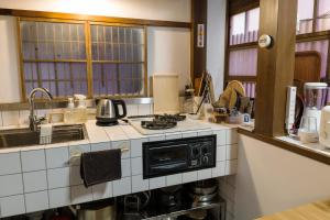 a kitchen with a stove and a microwave at Machiya Kanazawa Kikunoya in Kanazawa