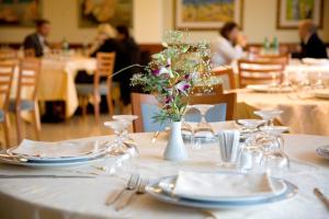 un tavolo con piatti e bicchieri e un vaso con fiori di Hotel Il Caminetto a Porto San Giorgio