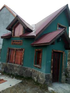 a green house with a red sign on it at La Protegida in El Chalten +3 photos