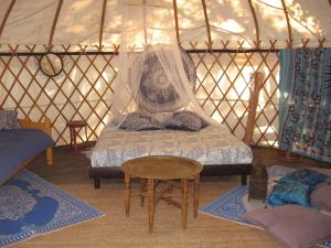 1 dormitorio con cama y mesa en una yurta en Camping Mille Étoiles, en Labastide-de-Virac