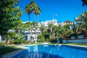 ベナアビスにあるappartement gelegen aan de golfbaan op La Quinta Benahavis Marbellaのヤシの木と建物を背景にしたスイミングプール