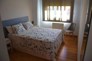 1 dormitorio con cama, ventana y silla en Piso ILLA DE AROUSA, RISON, en A Illa de Arousa