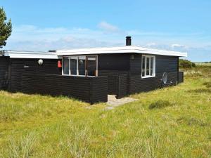 une maison noire assise sur une colline herbeuse dans l'établissement 4 person holiday home in Fan, à Fanø