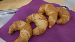 three croissants sitting on a purple cutting board at Hotel Pinger in Remagen