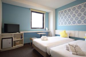 a hotel room with two beds and a flat screen tv at HOTEL EURASIA MAIHAMA ANNEX in Urayasu