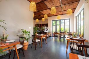 un restaurante con mesas y sillas de madera y ventanas en Tropical Home Villa, en Hoi An