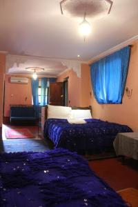 Habitación de hotel con 2 camas y cortinas azules en Chez Yacob Tamnougalt, en Agdz