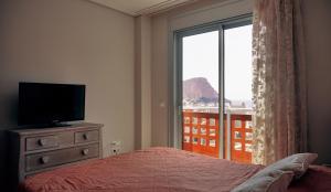 a bedroom with a bed and a tv and a window at Okeanos sea view 1 bedroom VR-S in Granadilla de Abona +23 photos