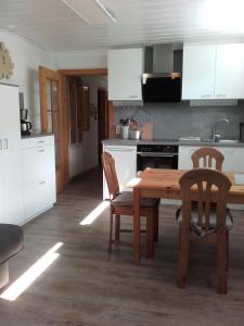 eine Küche mit einem Holztisch sowie einem Tisch und Stühlen in der Unterkunft Apartment Marianne in Bad Gastein