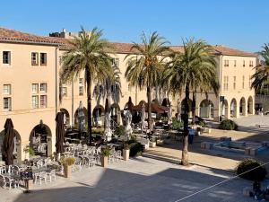 a courtyard with tables and palm trees in front of a building at Lou Mirèio in Aigues-Mortes