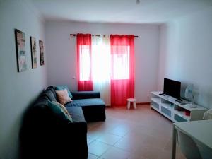 uma sala de estar com um sofá e cortinas vermelhas em Faro Island Beach & Airport Apartment em Faro