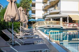 een zwembad met stoelen en parasols naast een gebouw bij Angela in Kos-stad