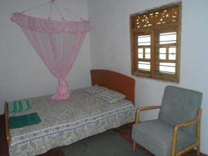 a bedroom with a bed and a chair and a window at El Shaddai in Mannar
