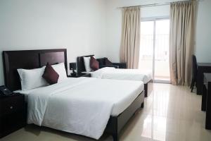 a hotel room with two beds and a large window at Aurak Guest House in Ras al Khaimah