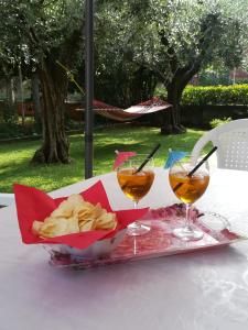 Appartamento Oasi Verde Lago في ديسينسانو ديل غاردا: سلة من الرقائق على طاولة مع كأسين من النبيذ