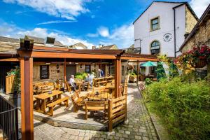 an outdoor patio with wooden tables and chairs at The Woolly Sheep Inn in Skipton