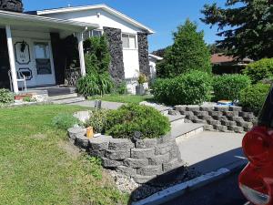 a house with a retaining wall in front of a yard at Bédard in Gatineau