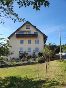 una grande casa bianca con un balcone sul lato di Chickenhill Blackforest, Ferienwohnung Großhans a Bad Wildbad