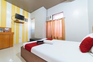 1 dormitorio con cama blanca y manta roja en RedDoorz @ Aparente Gensan, en General Santos
