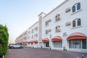 馬斯喀特的住宿－Hotel Summersands Al Wadi Al kabir，一座白色的大建筑,前面有汽车停放