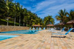 una piscina en el complejo con sillas y palmeras en Hotel Fazenda Villa Galicia, en Nazaré Paulista