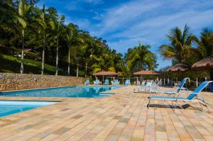 a pool at the resort with chairs and palm trees at Hotel Fazenda Villa Galicia in Nazaré Paulista