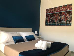 1 Schlafzimmer mit 2 Betten mit blauen Wänden und einem Gemälde in der Unterkunft CIVITAS 2 in Catania