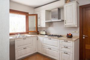 a kitchen with white cabinets and a sink and a window at Carrasqueta in Port d'Alcudia
