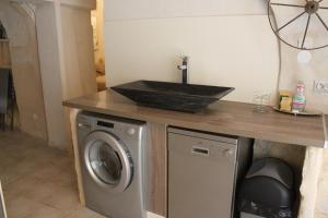 eine Küche mit einer Spüle und einer Waschmaschine in der Unterkunft maison de village in Saint-Quentin-la-Poterie