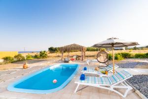 einen Pool mit Stühlen und Sonnenschirmen sowie einen Pool in der Unterkunft Gennadi Serenity House- beachfront villa with pool in Gennadi