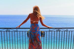 a woman standing on a balcony looking at the ocean at Park Hotel Silemi in Letojanni